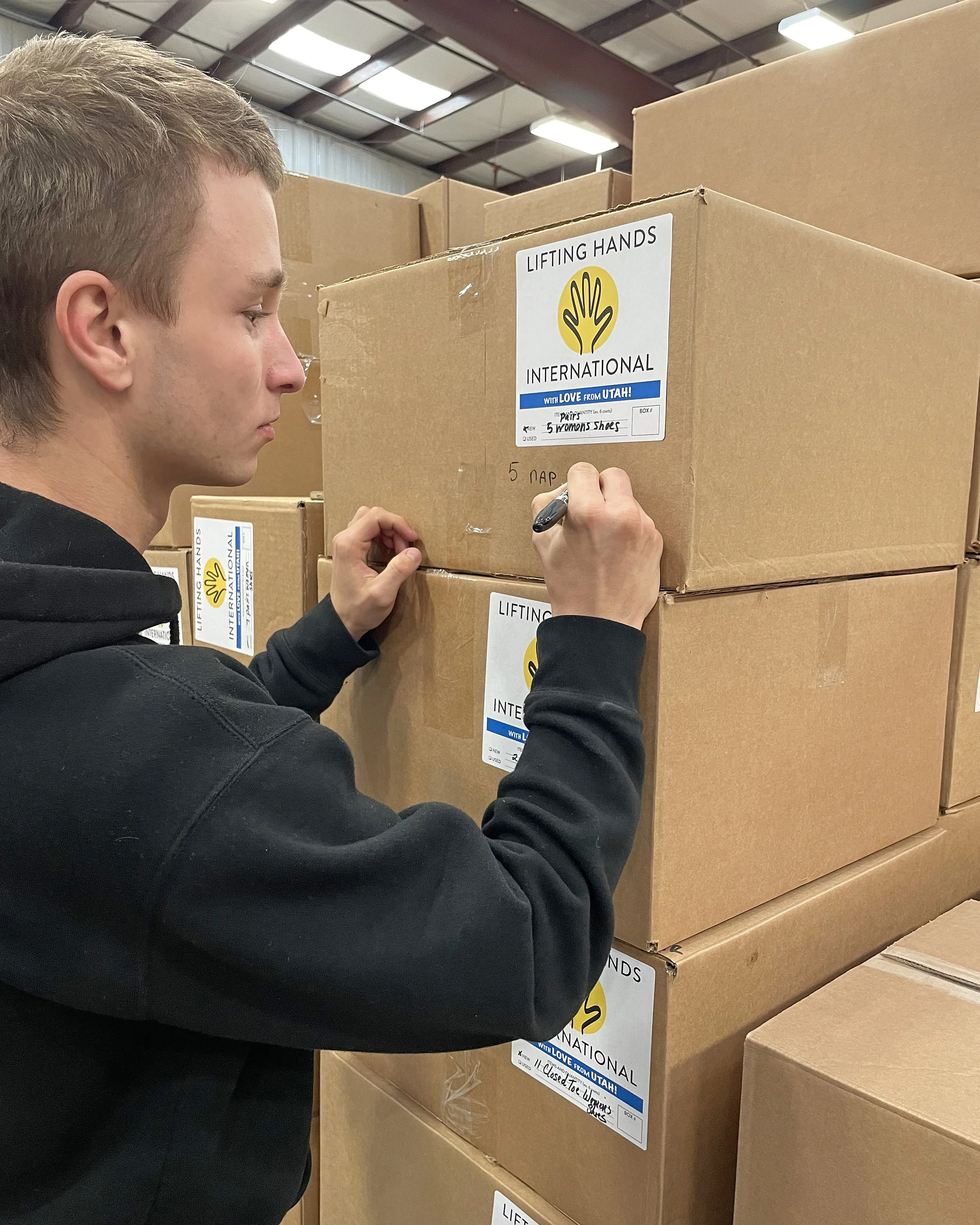  LHI Humanitarian Aid Warehouse volunteer Nikita helps to translate box labels into Ukranian. 