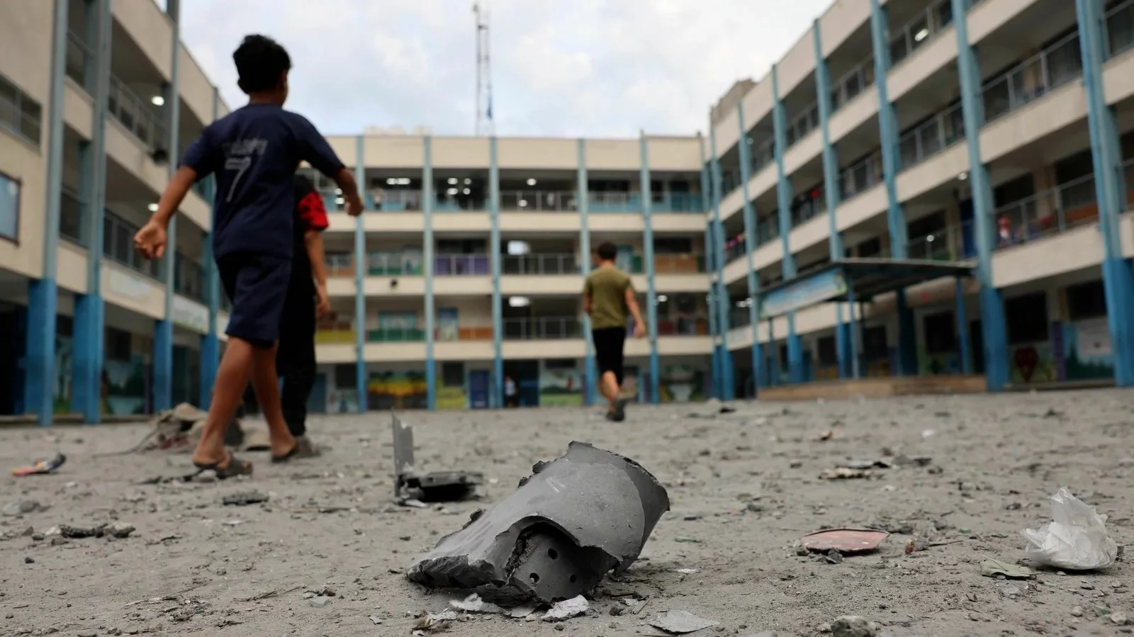  Children and families have sought refuge at schools run by the United Nations Relief and Works Agency within Gaza. These children walk amongst debris from a recent airstrike.  Image credit: Mohammed Abed/AFP via Getty Images 