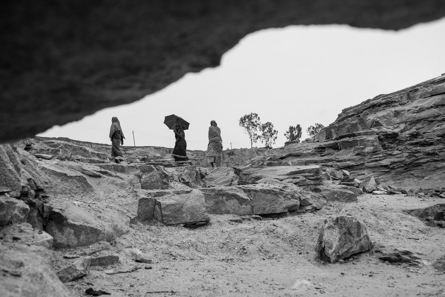Women workers make their way home as it begins to rain in a granite quarry in Rampura, just outside Bangalore, INDIA.