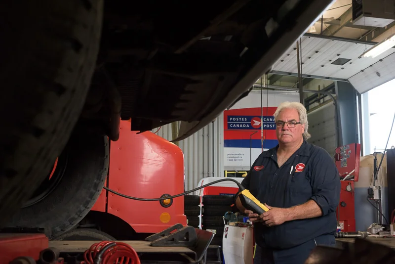 A mechanic overlooks a vehicle in for repair. Looking for interesting angles gives the viewer a greater sense of the environment of where the photo is taken. This is being light from the right to simulate the light entering from the overhead door.