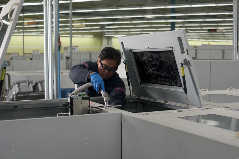 A worker cleans a large mail sorting machine. I used side lighting in this image to create contrast in the subject.