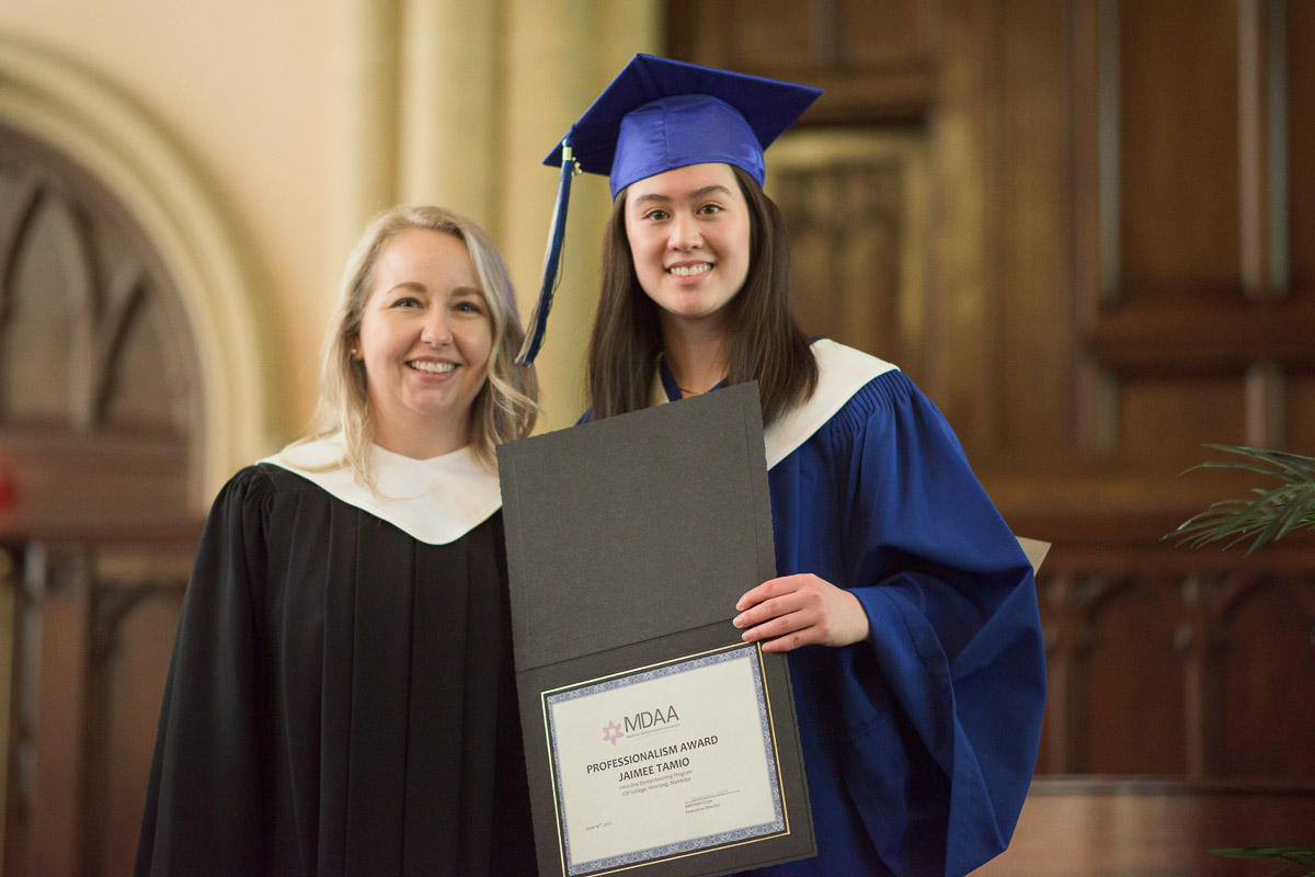 An instructor poses with a student holding an award certificate.