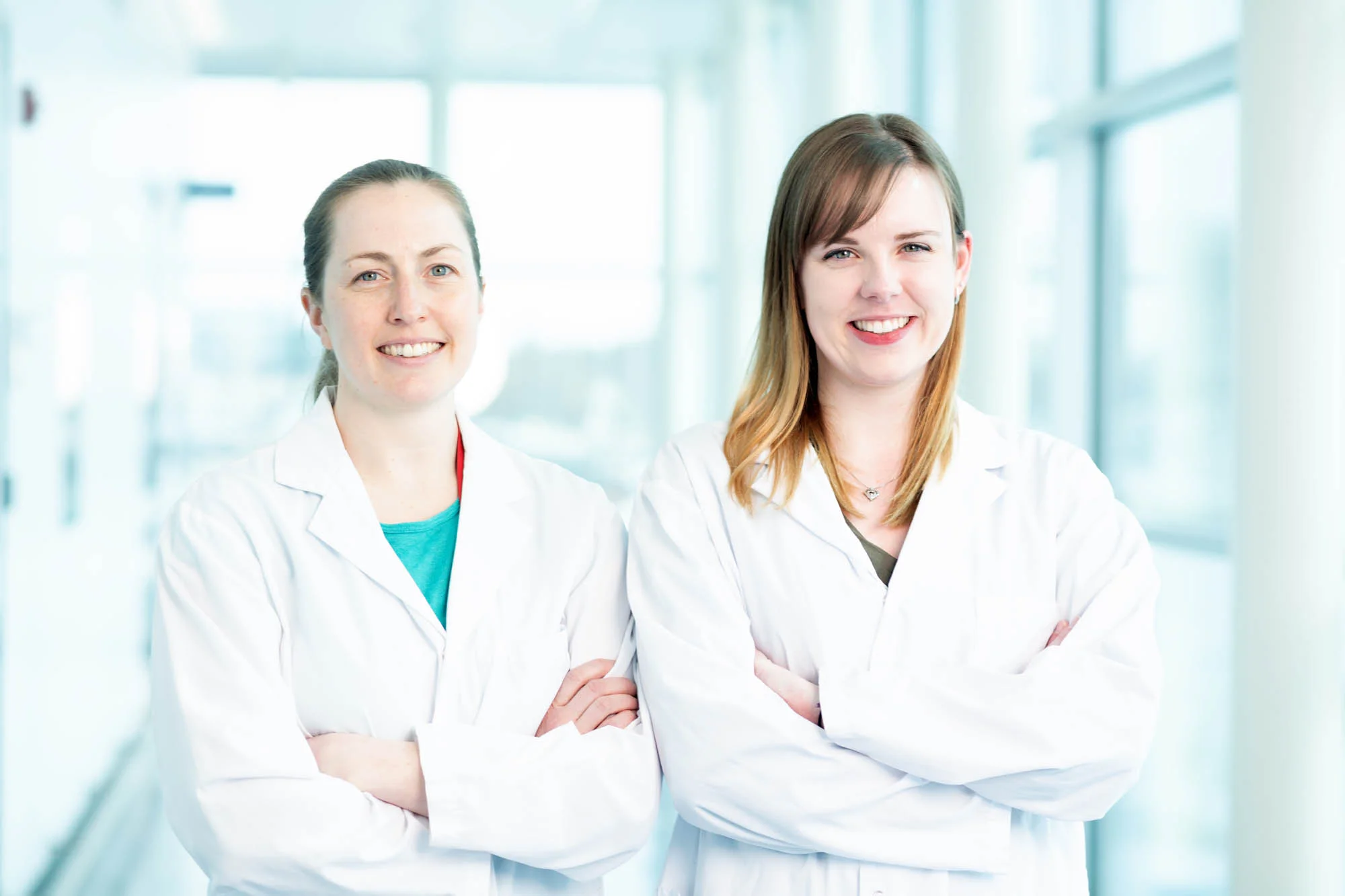 Two researchers pose for a photo in the hallway of a large medical facility. © Robert Lowdon