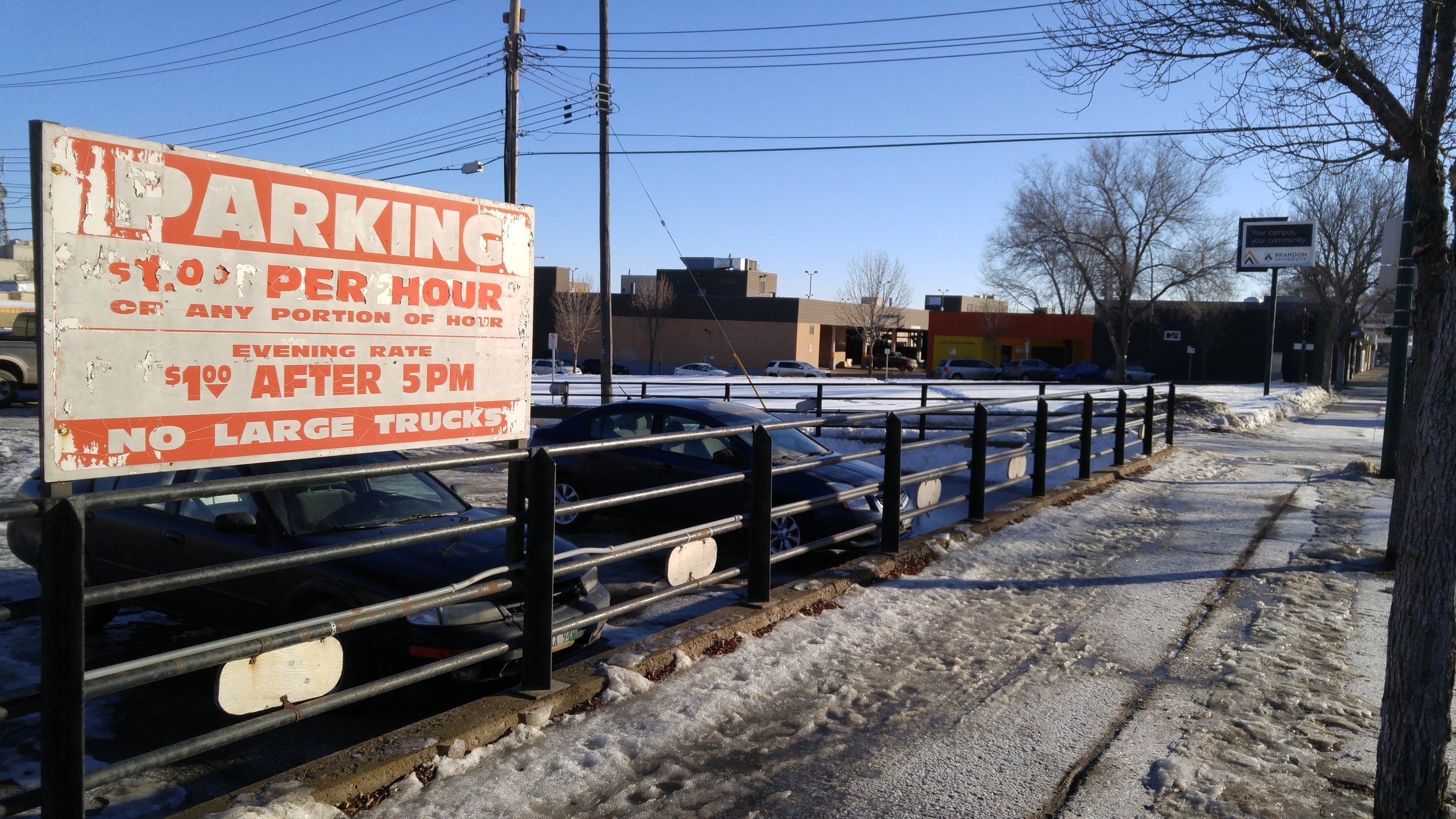 The parking lot at 149 10th Street, with the new Brandon University sign on 901 Princess Avenue in the background. (Credit: Logan Praznik/The Quill)