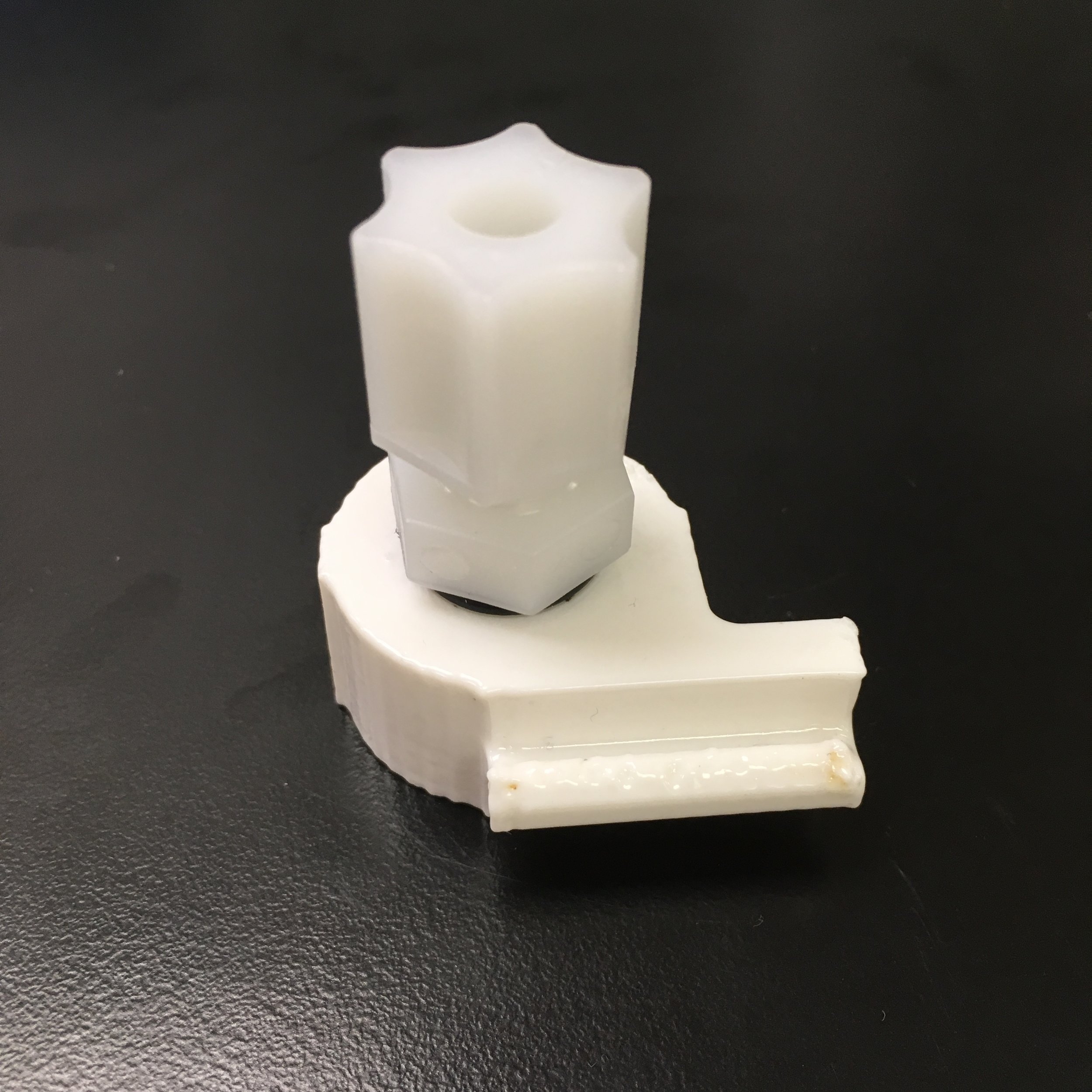An FDM Printed Bag Cap with an NPT x Compression Fitting attached. It has been post-processed with acetone vapor to smooth the outer surface.