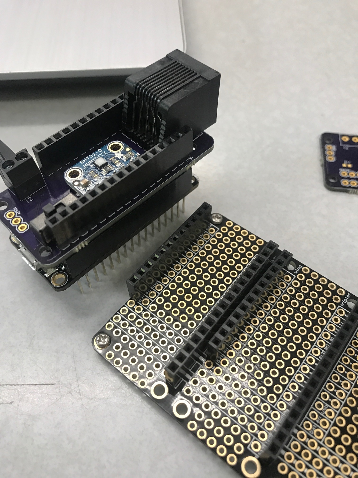 Stack the custom PCB construction on top of the Feather M0 with LoRa as shown, and solder female pins on the FeatherWing Tripler as shown.&nbsp;