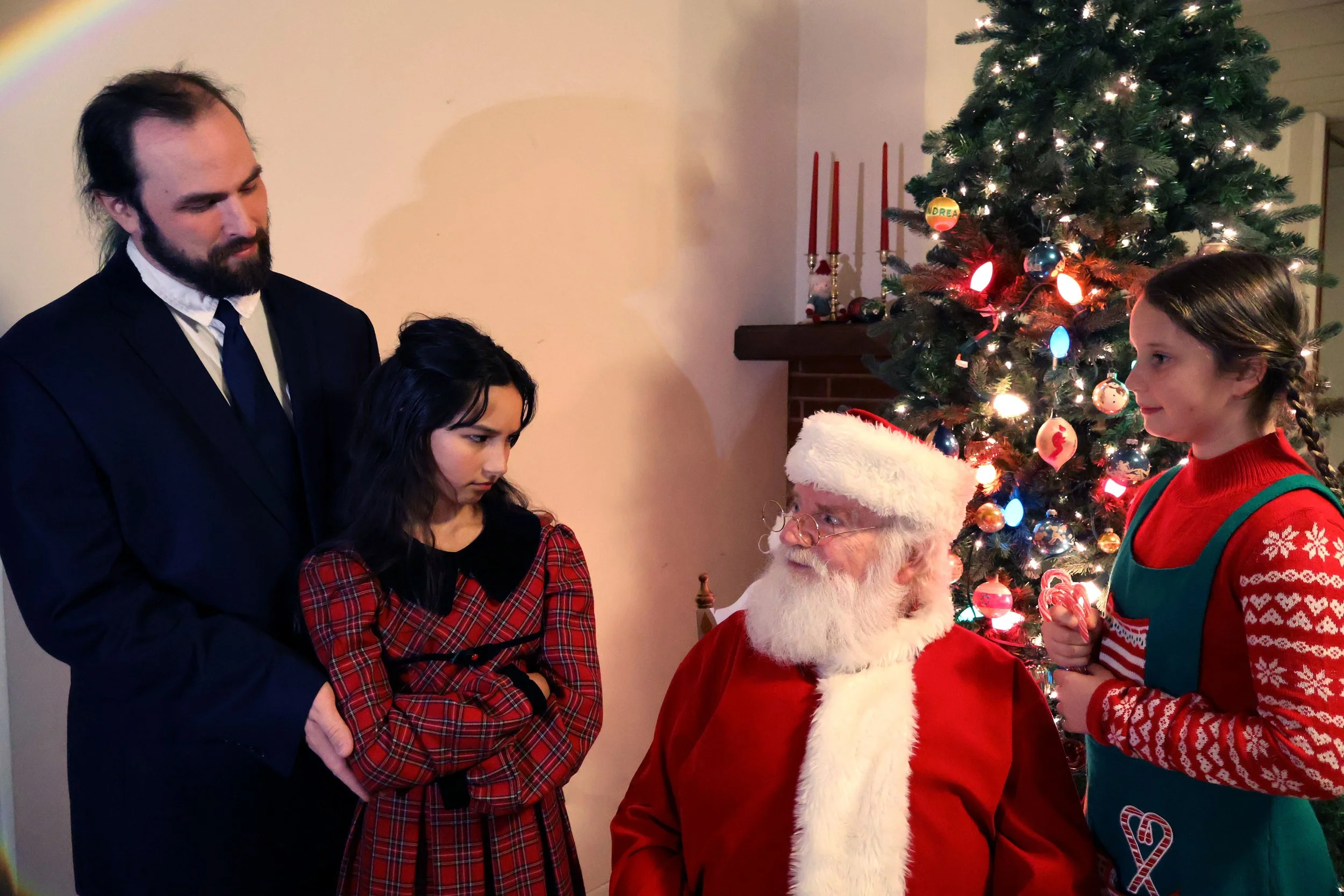 Show photo from Miracle on 34th Street with a family looking at Santa and an elf.