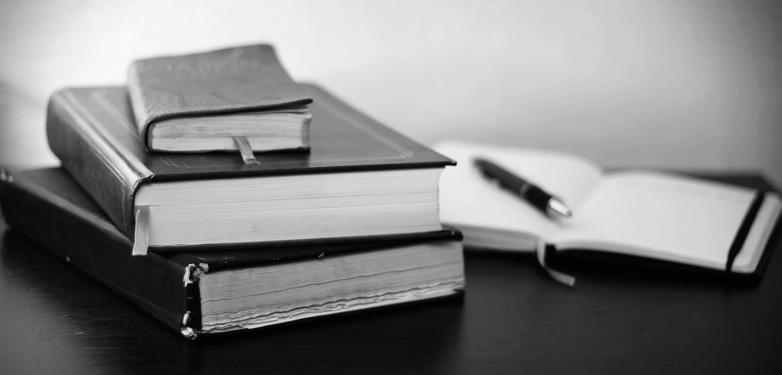 pile-of-books-on-table-with-notebook-and-ball-pen.jpg