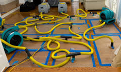 Image shows water damage restoration equipment attached to flooring.