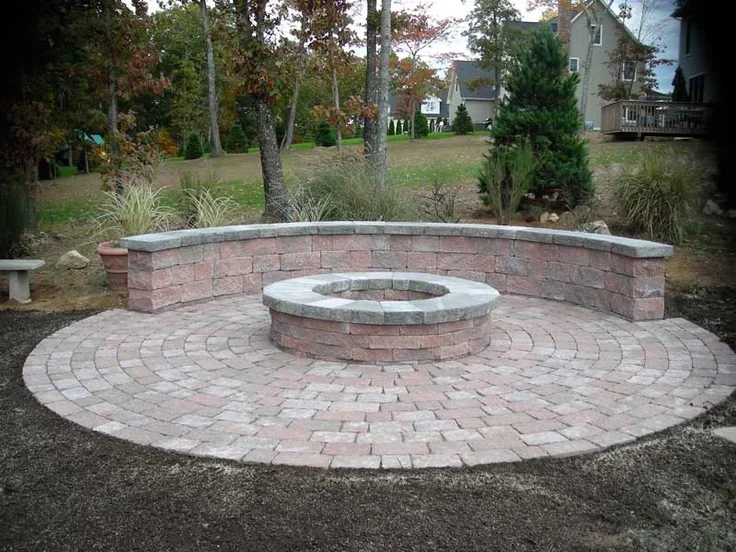 A circular brick area with bult-in seating half way around a brick fire pit.