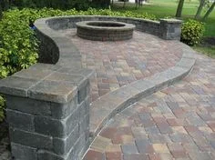 A raised section brick section with built-in seating and circular fire pit.