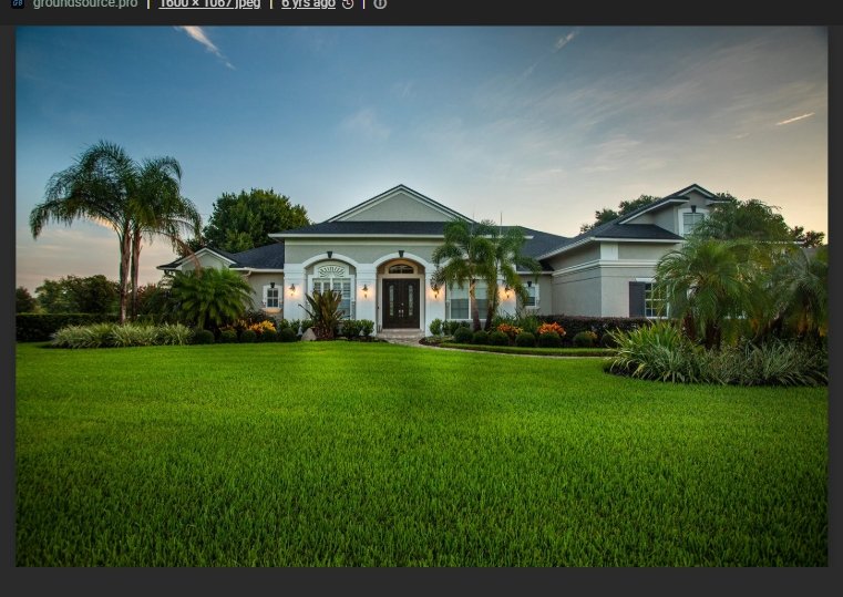 Large modern house with a well-maintained front lawn and tropical palm trees, under a partly cloudy sky during sunset.