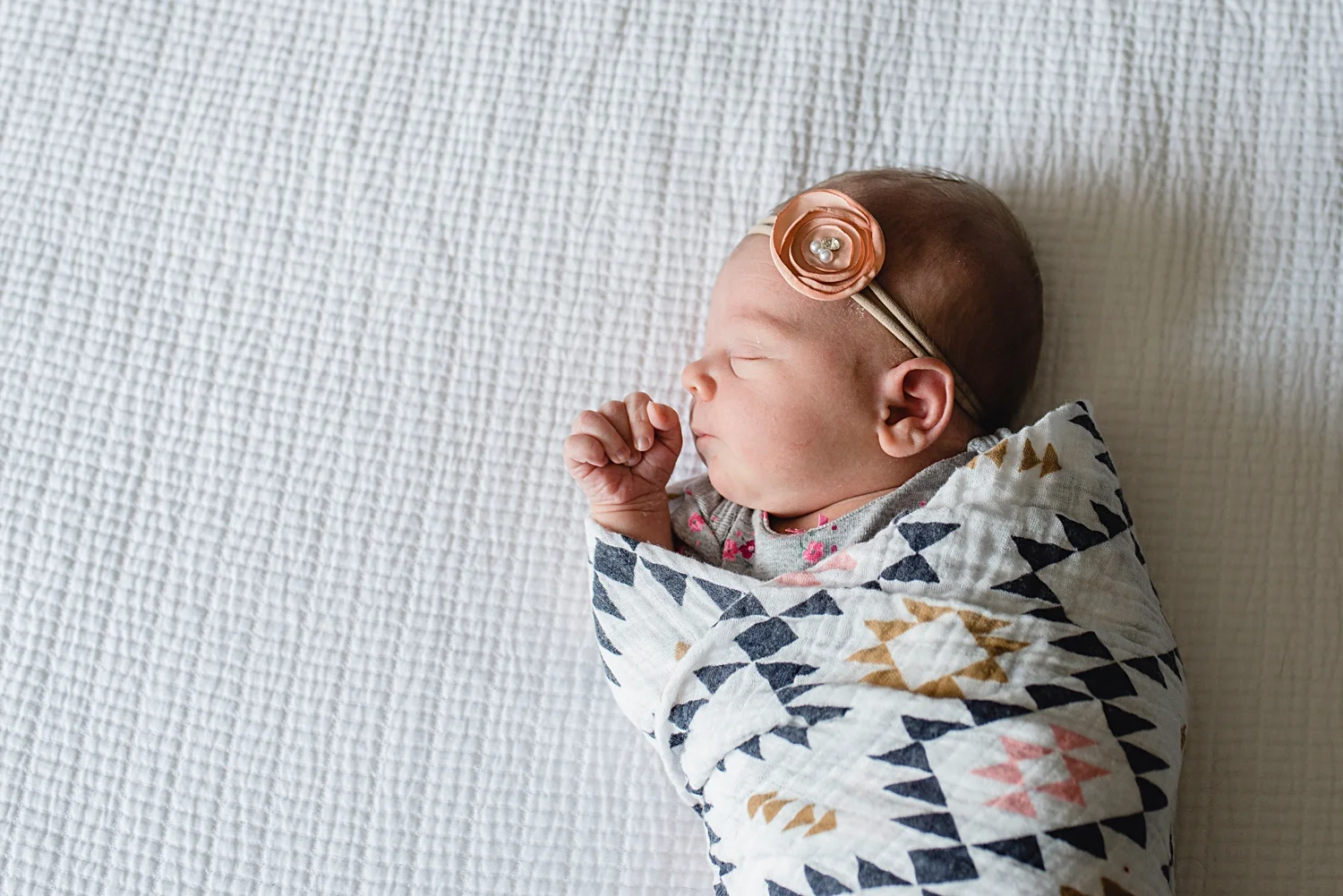 A newborn baby girl is swaddled in an Aztec printed baby wrap during a Highlands Ranch Newborn Baby Photo Shoot in South Denver with Kristiina Craven Photography. #denvernewbornphotographer