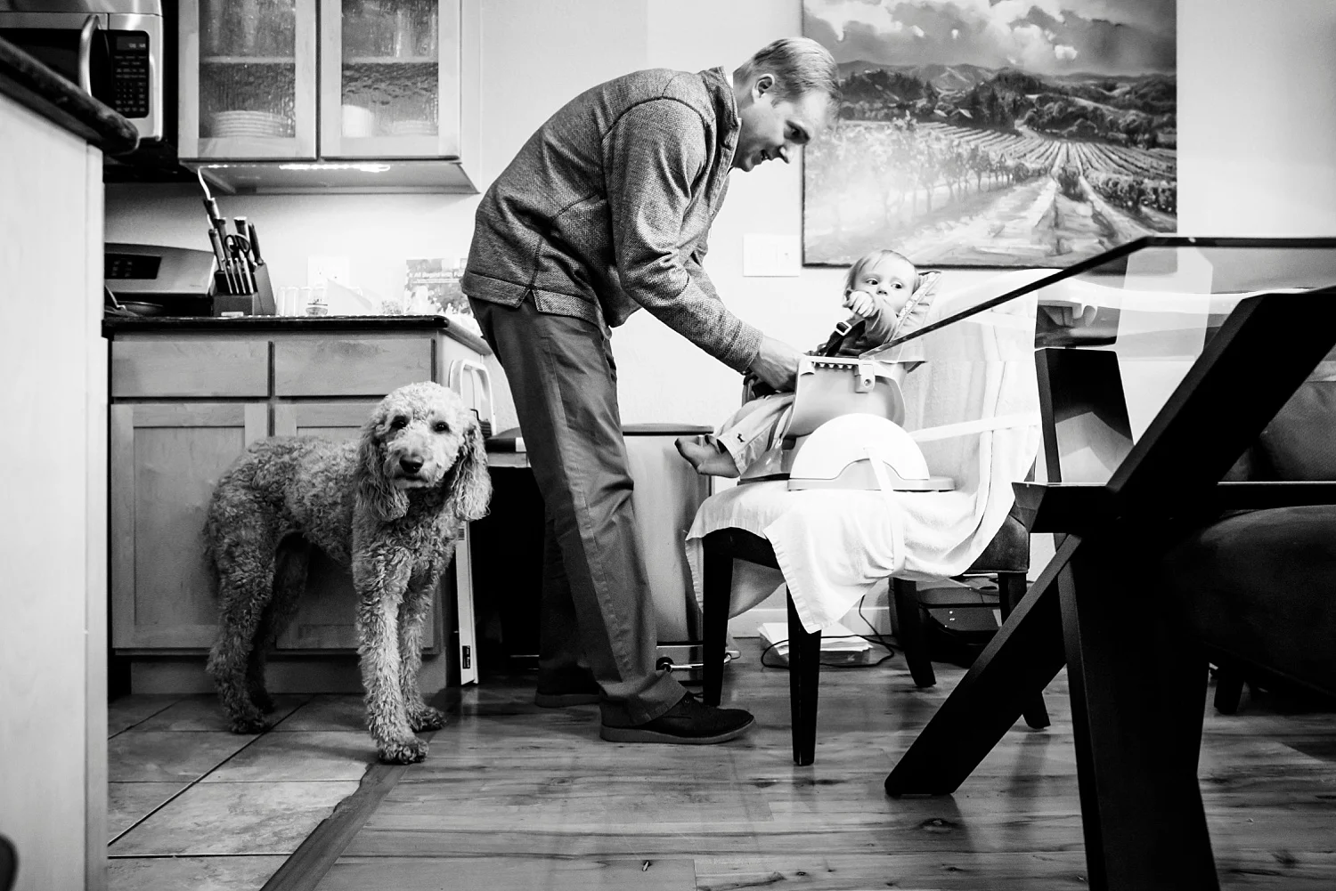 A father feeds his toddler son in Denver, Colorado. Black and white family photography.