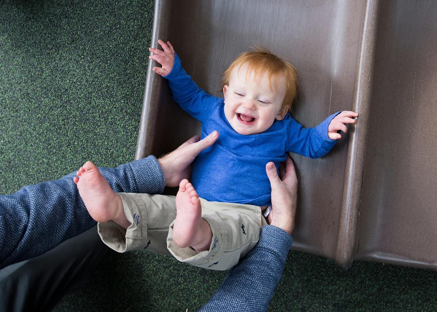 A toddler laughs while going down a slide at a park in Denver, Colorado.