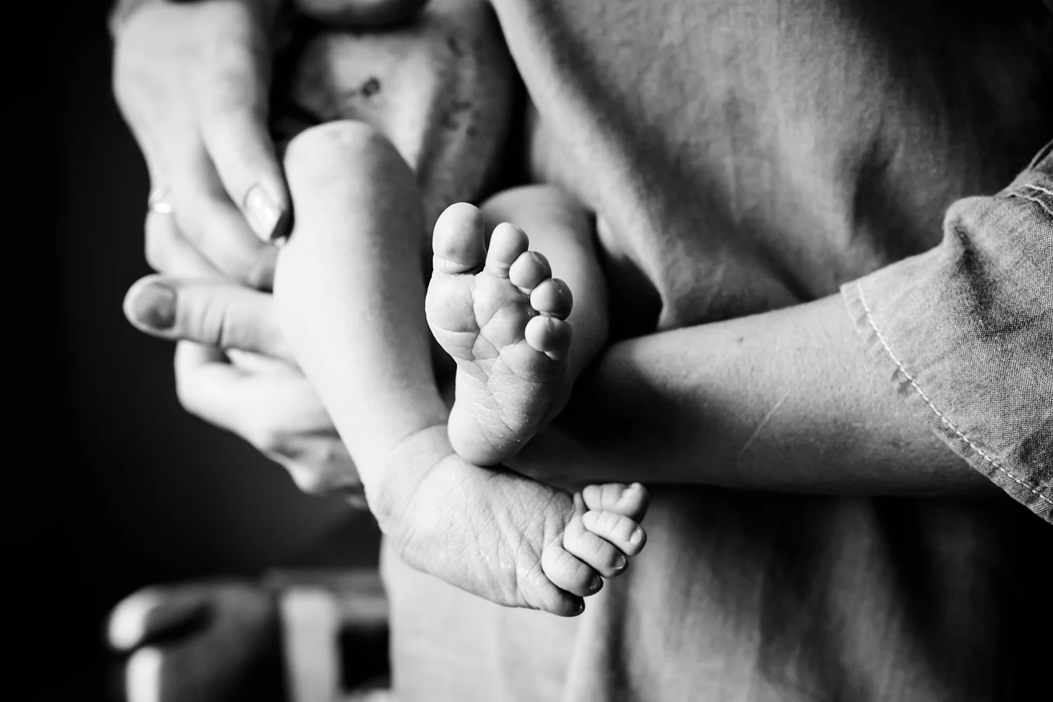 A mom holds her newborn baby in a black and white image by Kristiina Craven Photography. She reviews what it was like working for Bella Baby Photography.