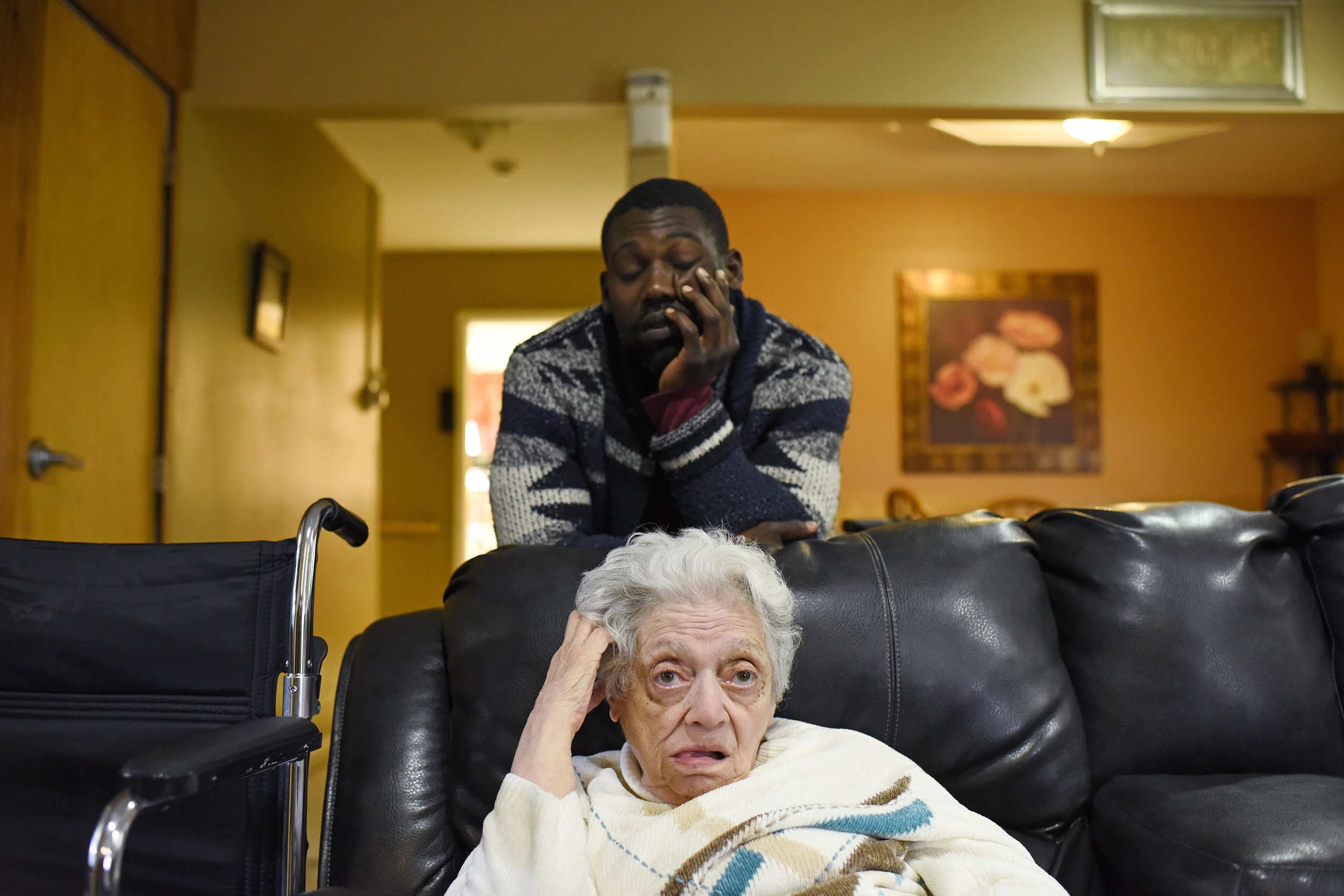  Relief day service provider, Maurice Thomson (29), sits behind Evelyn Vius (83) at a Sullivan Arc residential house in Woodridge, New York on Oct. 9, 2016. (Courtney Pedroza/Eddie Adams Workshop) 