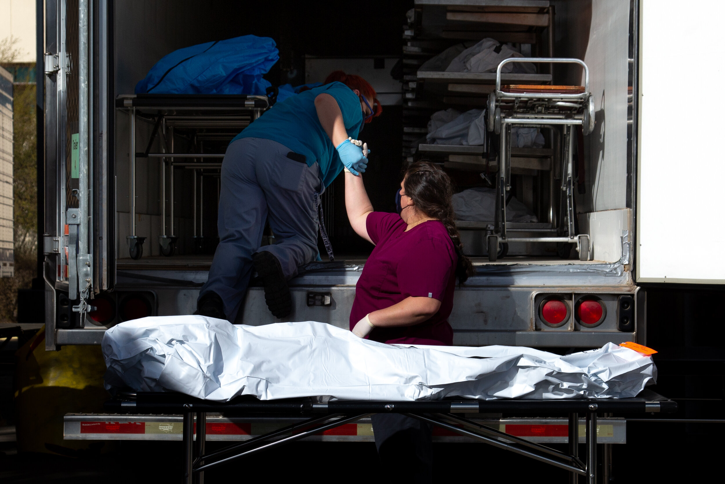  Employees of the Pima County Medical Examiner's office prepare to move a body into a refrigerated semi-truck at the Pima County Office of the Medical Examiner on January 14, 2021 in Tucson, Arizona. After reaching capacity amid the COVID-19 pandemic