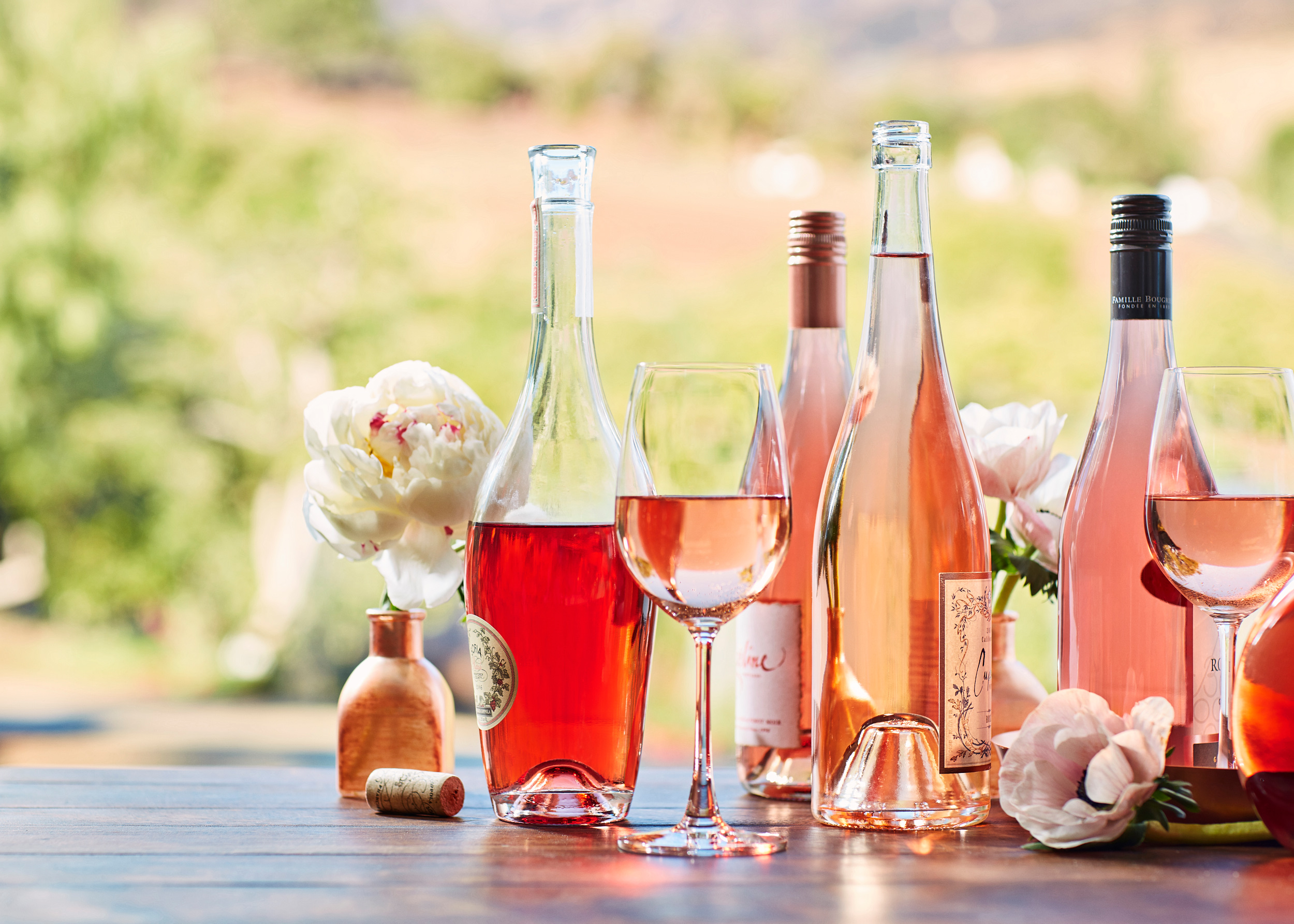 A collection of various Rosé wine bottles in an outdoor setting in the spring.