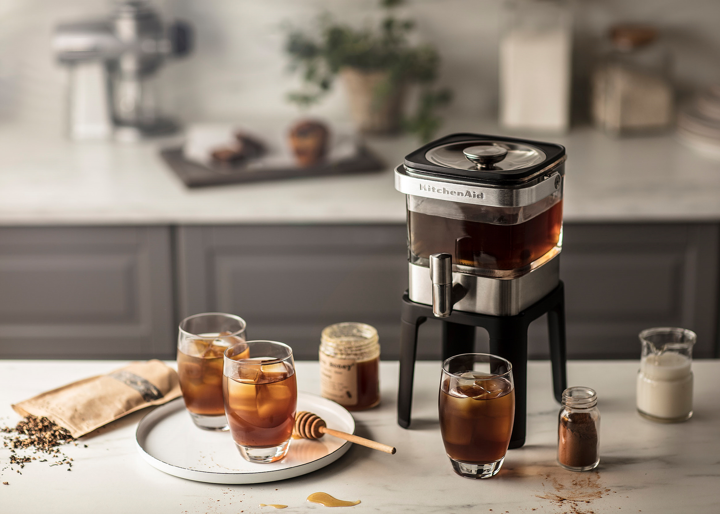 Iced tea in cold brewer with milk, honey and sugar in an at home setting.