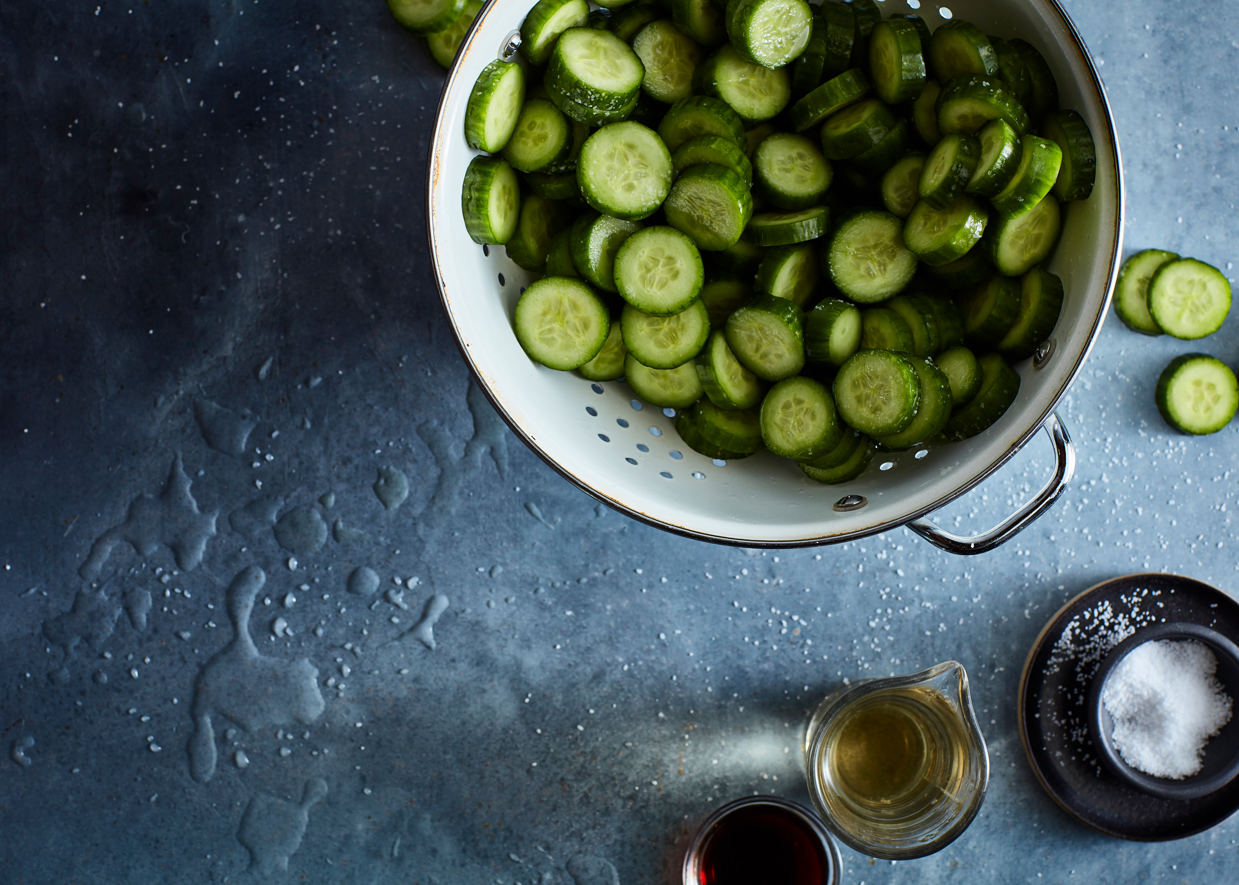 Prepping and jarring pickles on a wet surface with salt and vinegar. Moody, cool color temperature lighting.