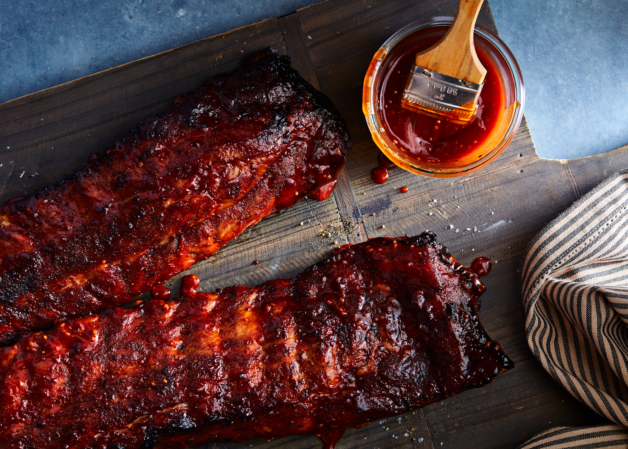 Baby Back Ribs and Barbecue Sauce on a cutting board.