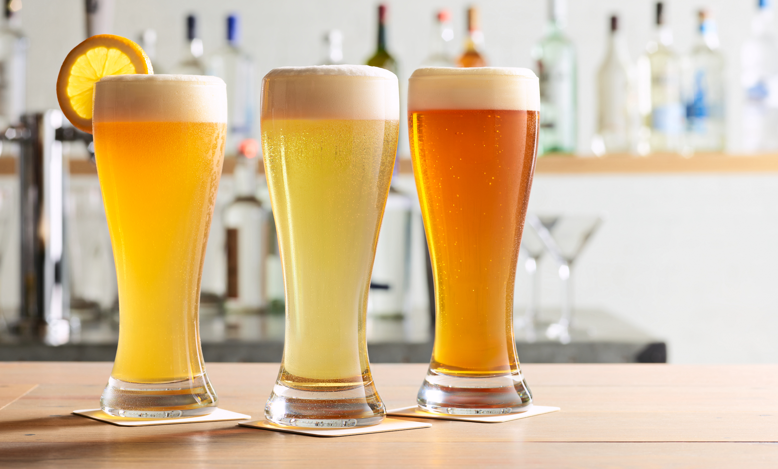 Three varieties of beers in a bar setting in a spectrum of colors.