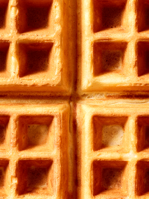 Animated GIF of a closeup of a Belgian waffle with maple syrup and butter.