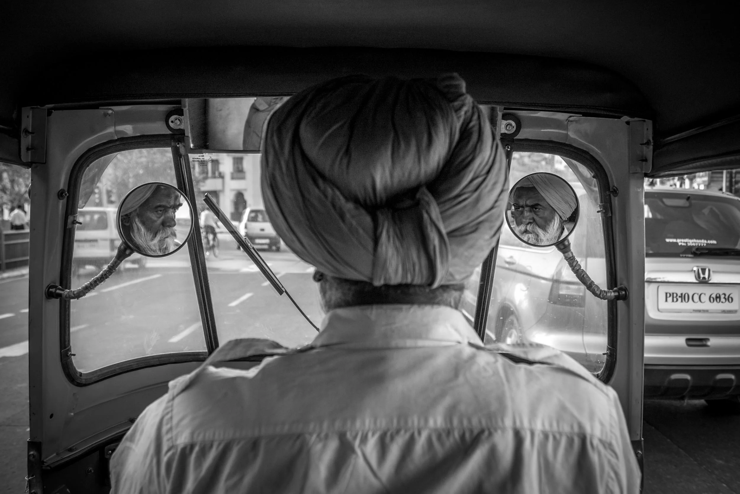 SIKH RIKSHAW DRIVER. THE FUNNY THING IS HIS SIDEVIEW MIRRORS ARE AIMED AT THE PASSENGER(ME) WHICH I IDIDN'T MIND AS IT MADE FOR AN INTERESTING PHOTO. NEW DELHI, INDIA.
