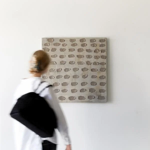 A viewer takes time to look at Kim Fonder's abstract artwork  Visone Uno, a neutral palette modern painting that measures 30 inches by 30 inches