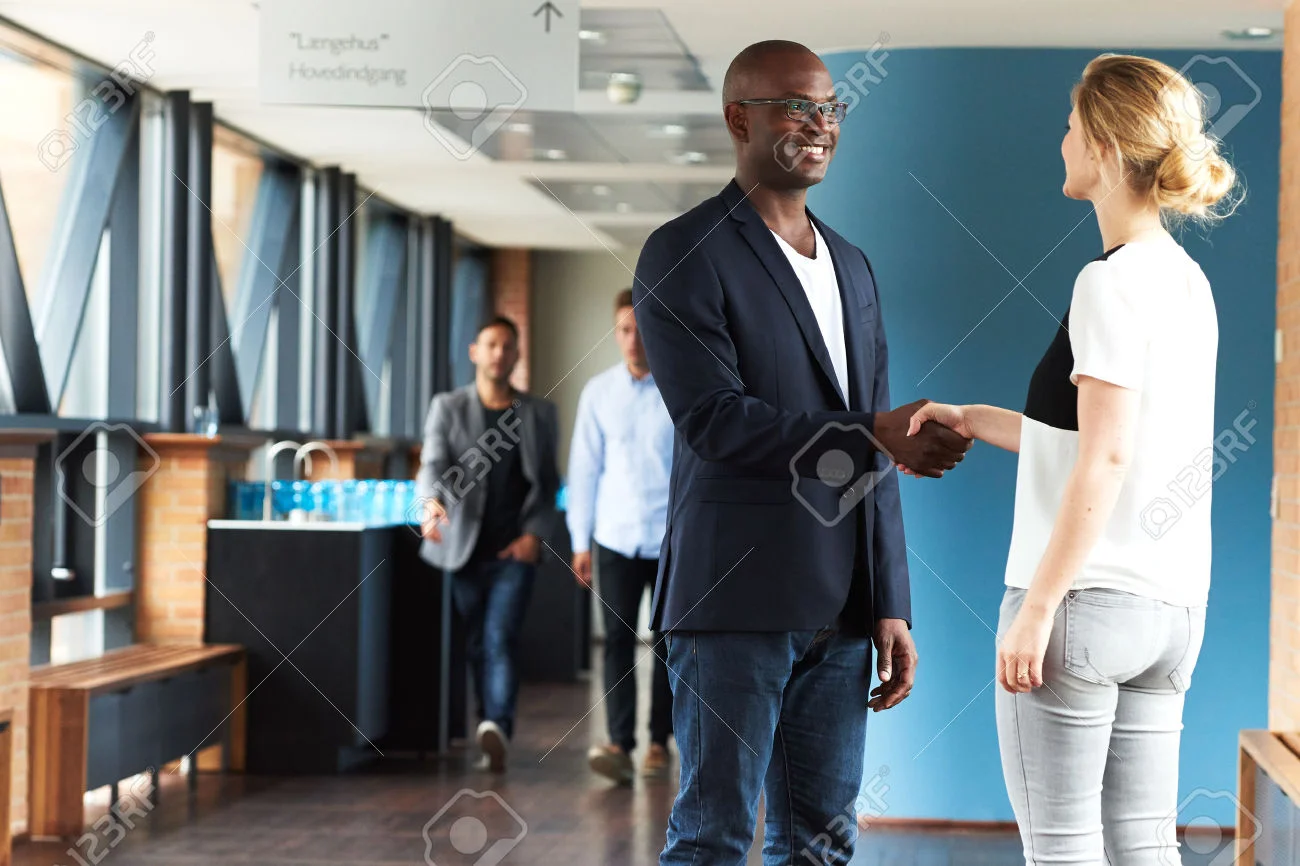 41683451-Black-man-and-white-woman-smiling-and-shaking-hands-in-office-building-Stock-Photo.jpg
