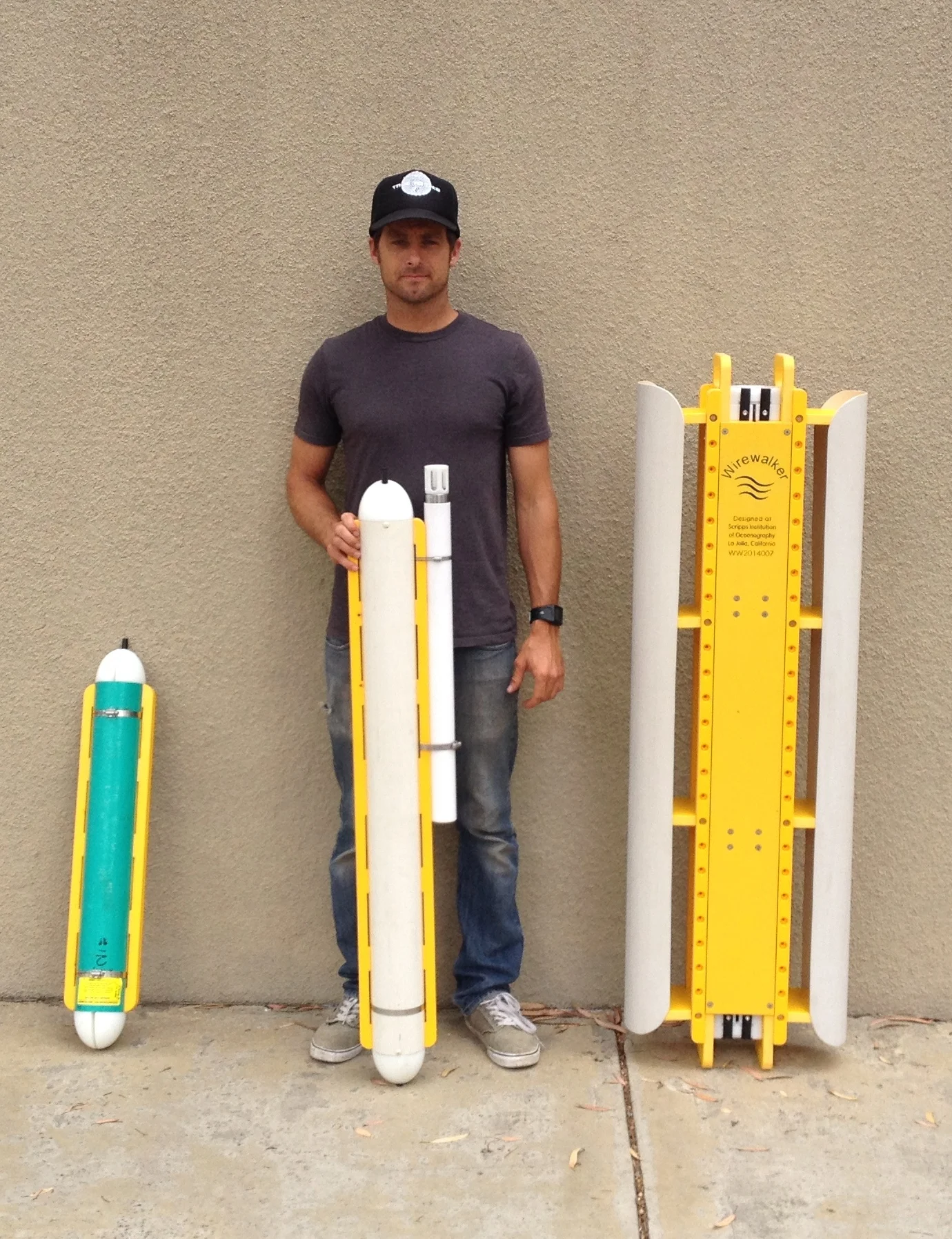MOD Development engineer, Tyler Hughen, with the three sizes of the Wirewalker wave-powered profiling vehicle.