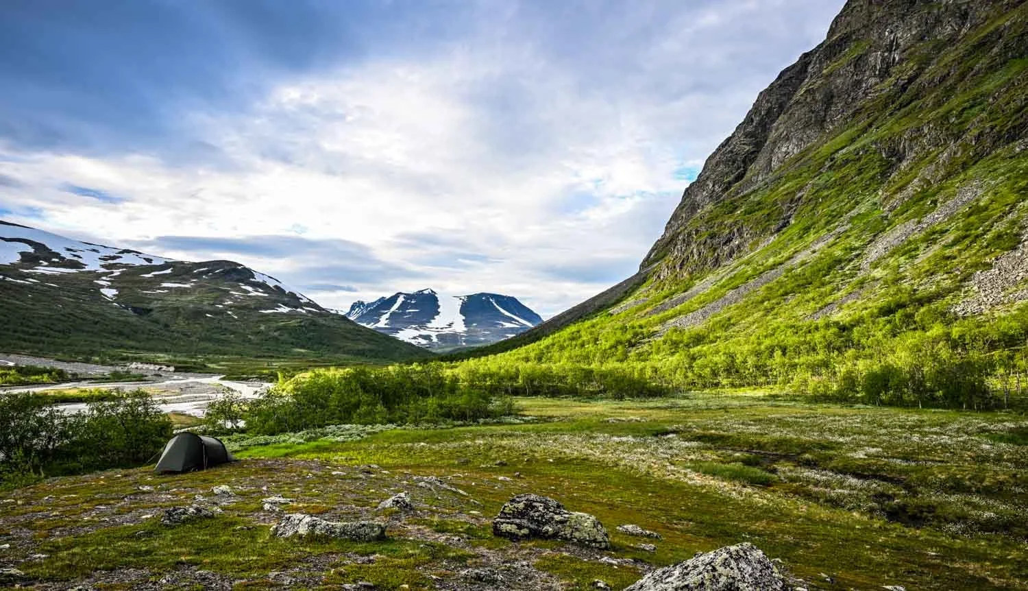 Grünes Flusstal mit Zelt in den Bergen des Sareks Nationalparks, Schweden