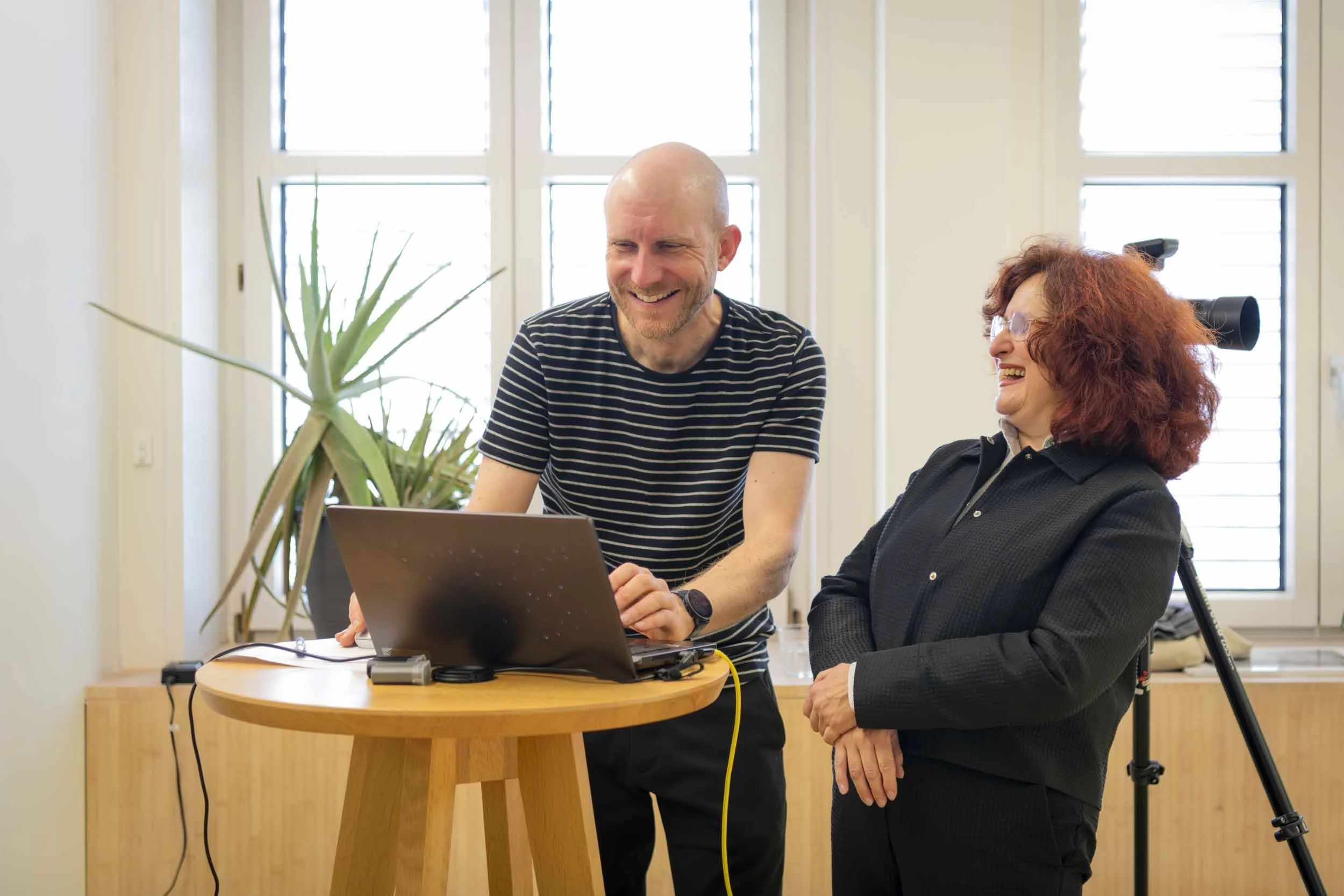Fotograf und Mitarbeitende lachend bei Bildbetrachtung des Business-Portraits