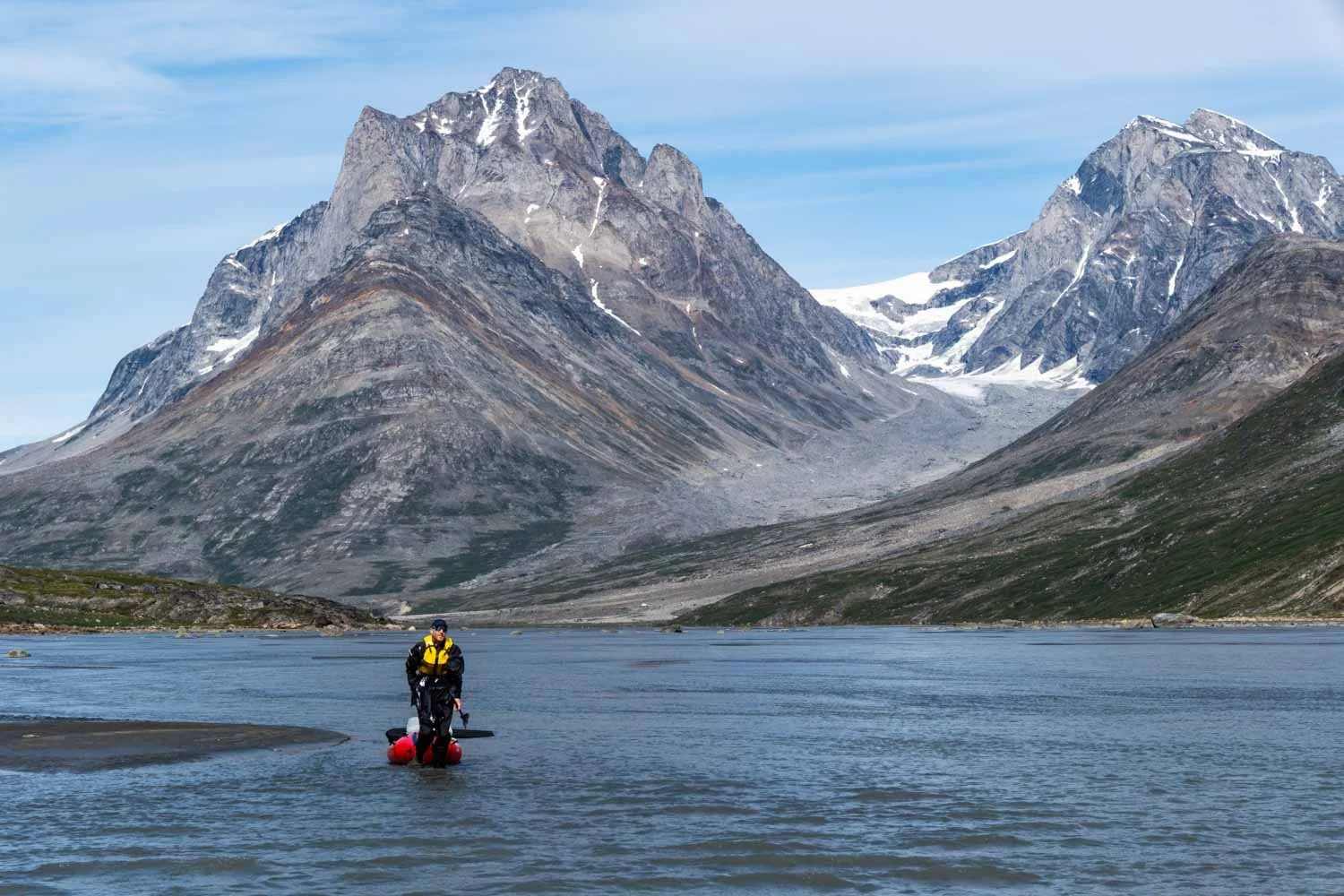 Fotograf Martin Ramsauer zieht sein Packraft durch einen seichten Fluss in Grönland