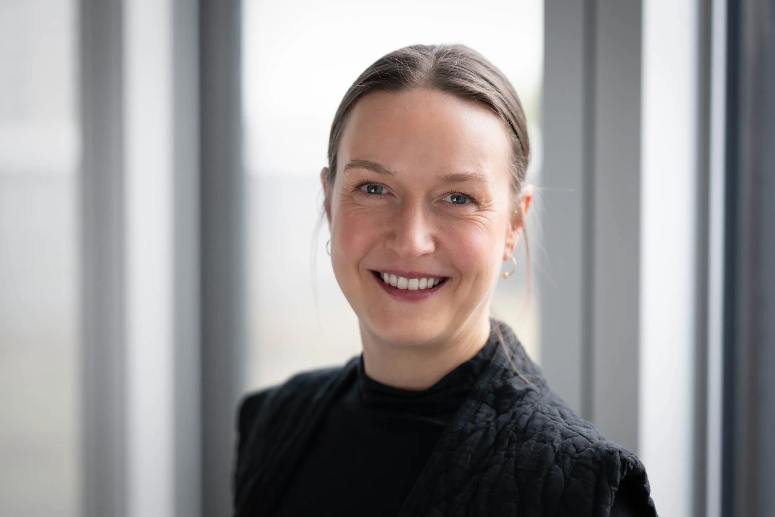 Professionelles Bewerbungsfoto einer Frau vor hellem Fensterlicht in Zürich