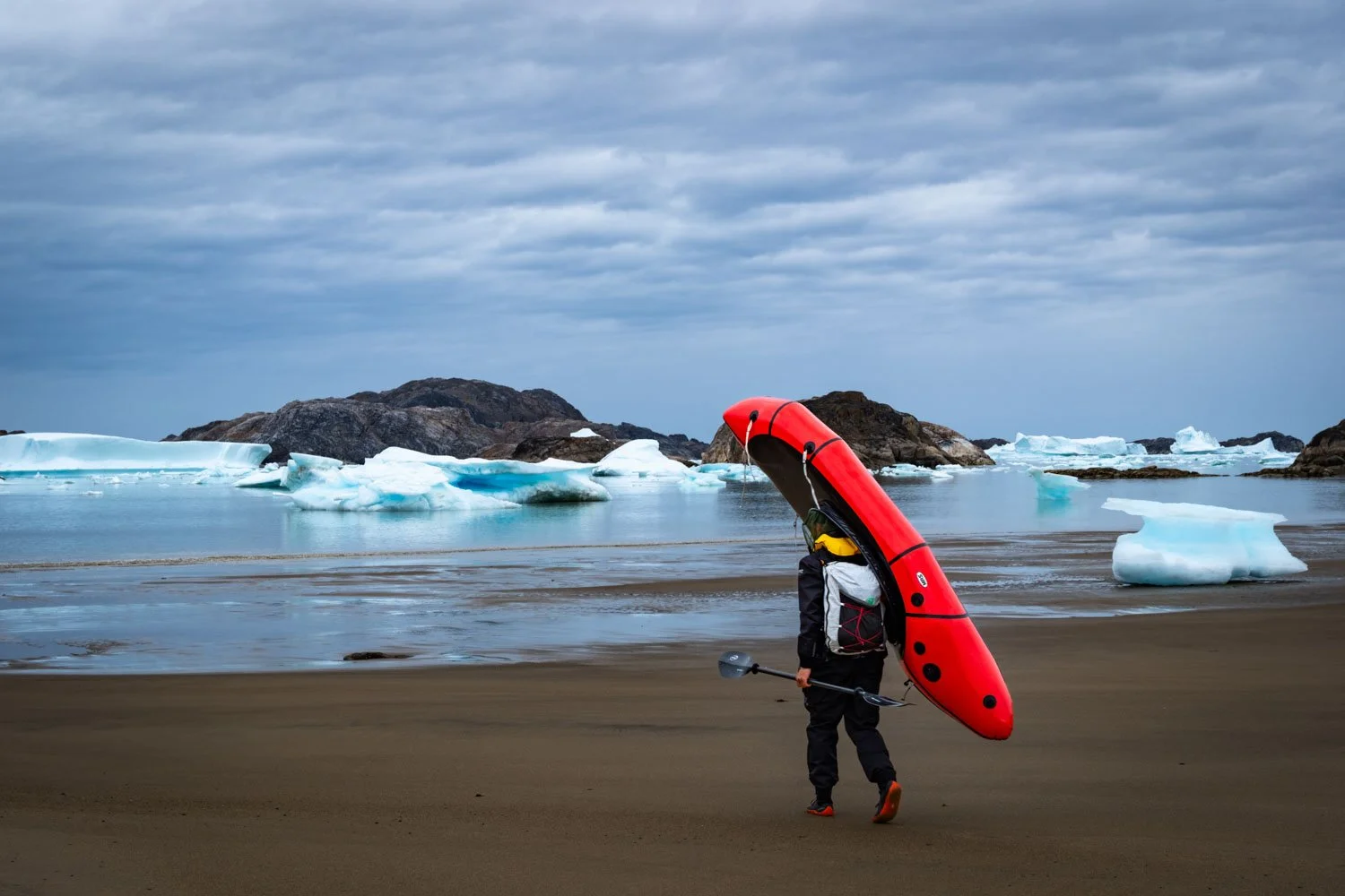 Martin Ramsauer schulter sein Packraft zum mit Eisbergen versetzten Fjord