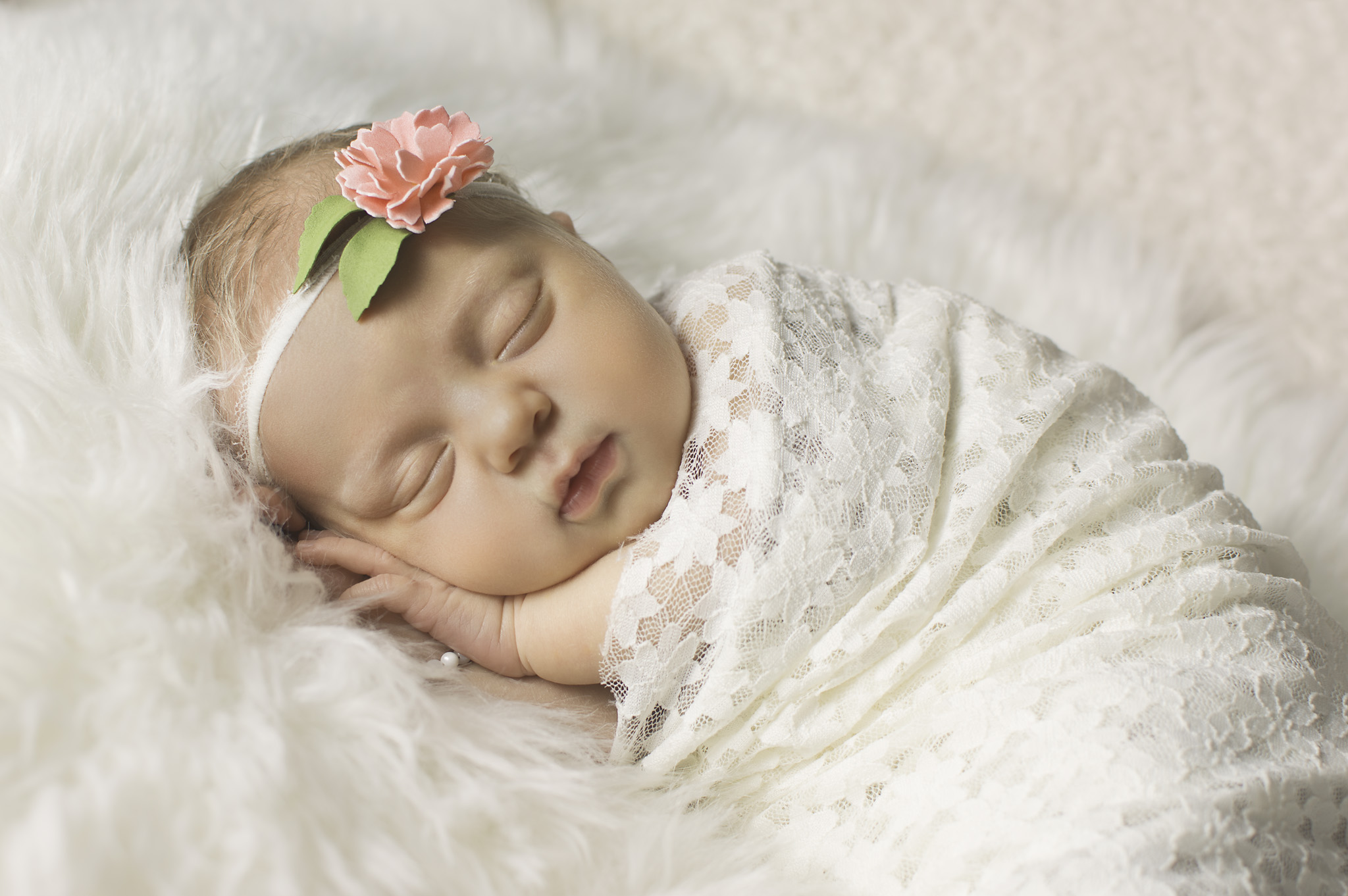 newborn wrapped in white lace with flower headband