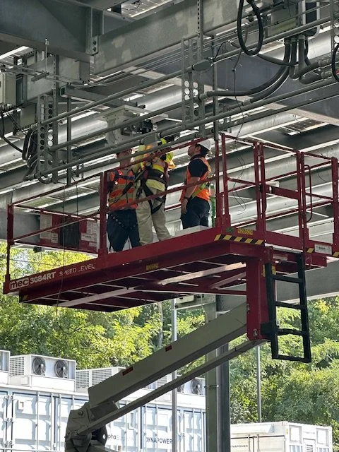 Crew installing electric bus chargers under a solar canopy
