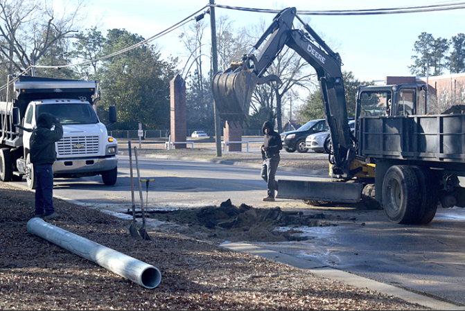 Garrett Bullock, Jaquan Jones and Ethan Dudney work at the site of the water line break on Lee Street.