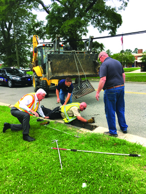Animal Control Officer Darryl Hooker goes into the storm drain to save a calico kitten Tuesday. Fire Marshall Hal Lowder monitors the rescue with Travis Faulk and Mark Coleman of the city’s Public Works Department.