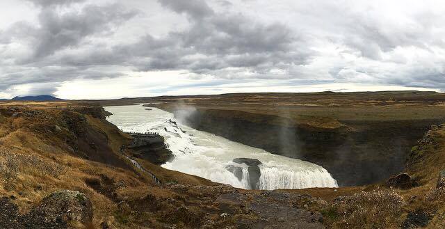 View of the Gollfoss Waterfall in it's entirety; notice the vast open & untouched landscape. The small figures lining the rock below the top of the waterfall are people!