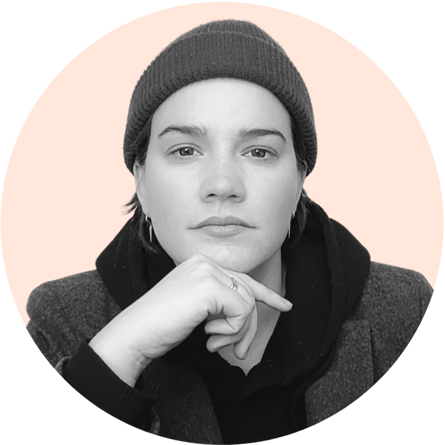 Black and white portrait of a woman with short hair, wearing a beanie and jacket, resting her chin on her hand, against a pink circular background. Tattoo Artist. Amsterdam.