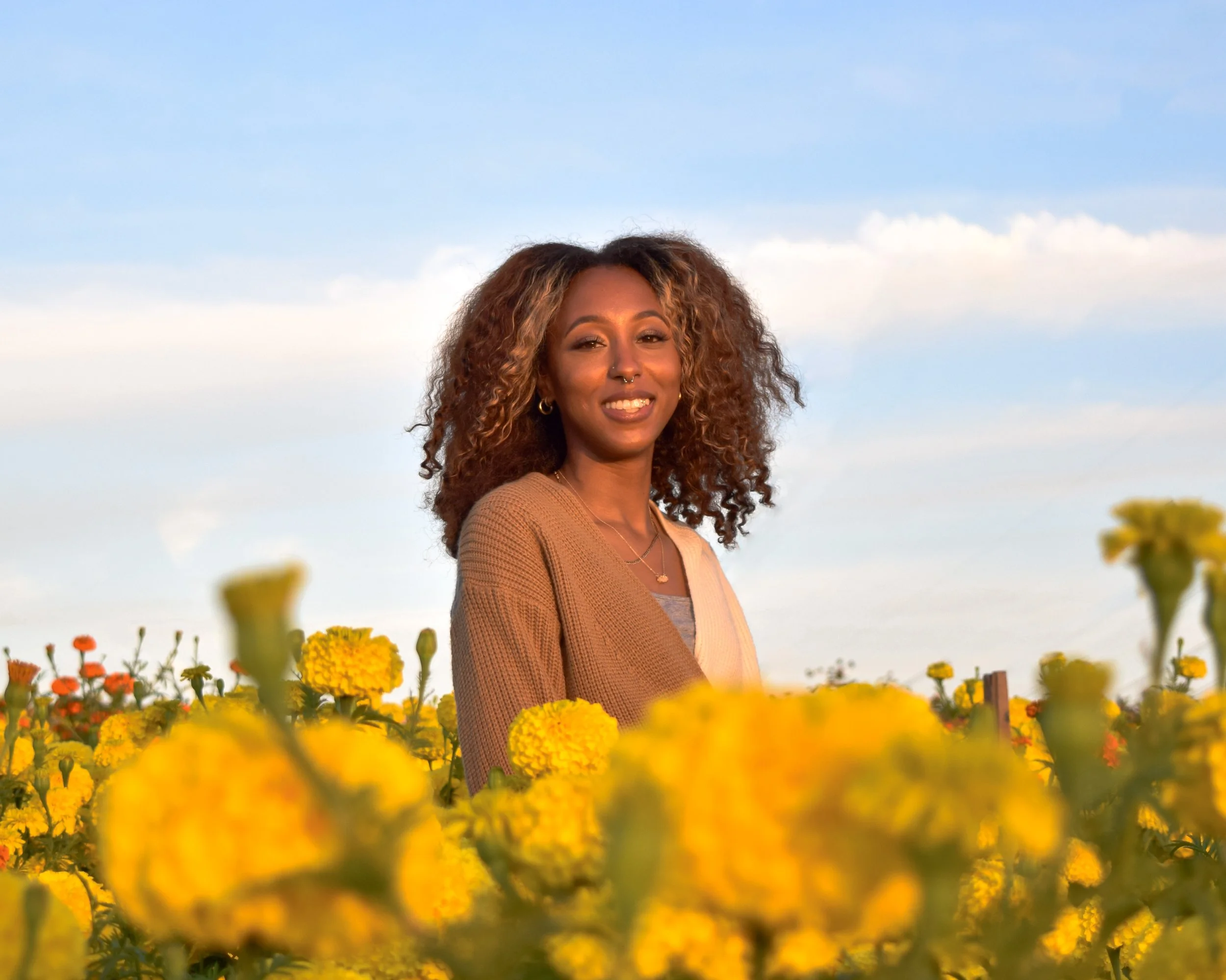 Lauren Williams, certified overnight postpartum doula at Night & Day San Diego smiling among flowers outside.