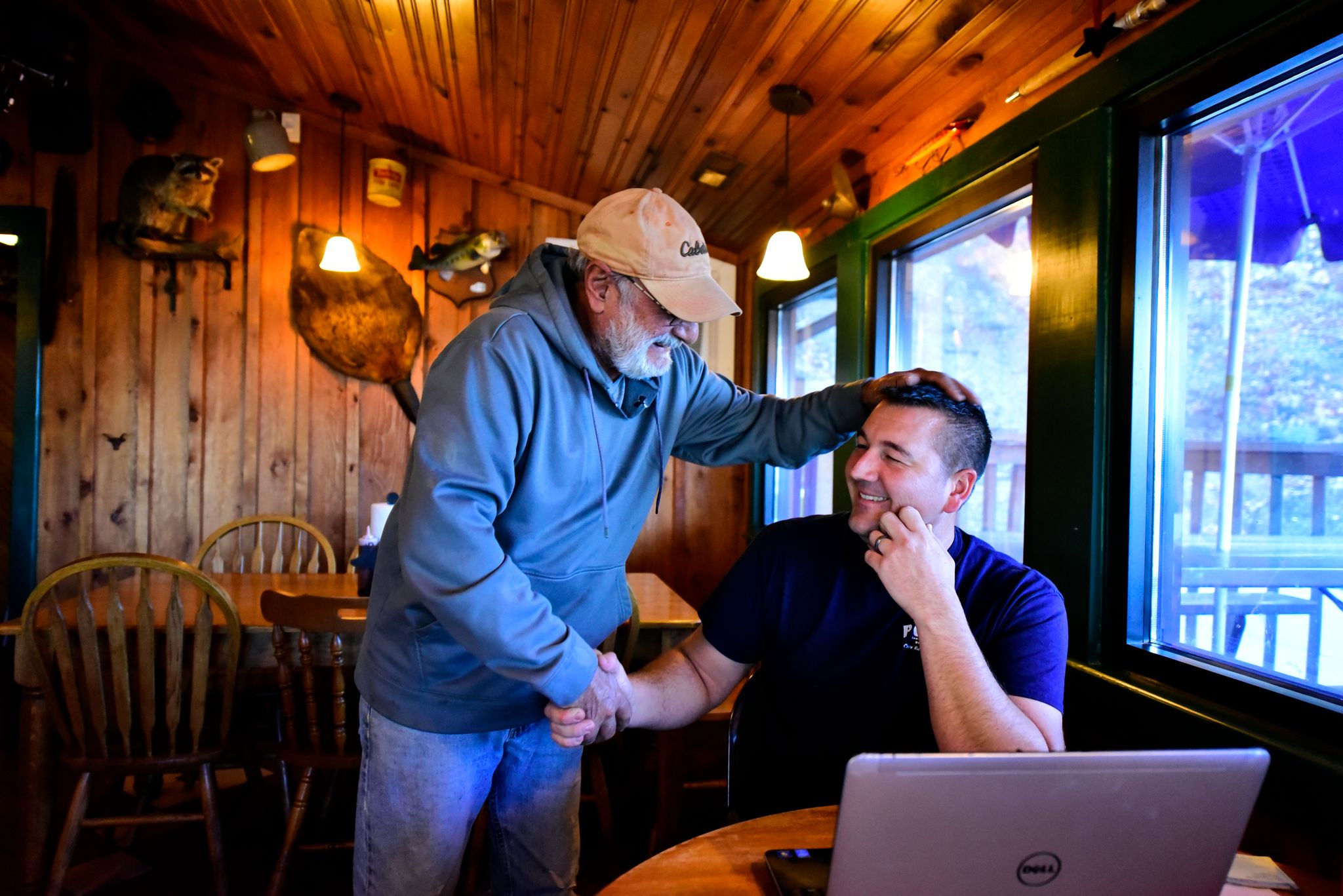 Mike Winer, left, a Pop's BBQ regular, greets Adam. Adam fosters the values of community and family at Pop's. "Sometimes he comes in for five minutes to talk, sometimes it's 30 minutes," says Adam.