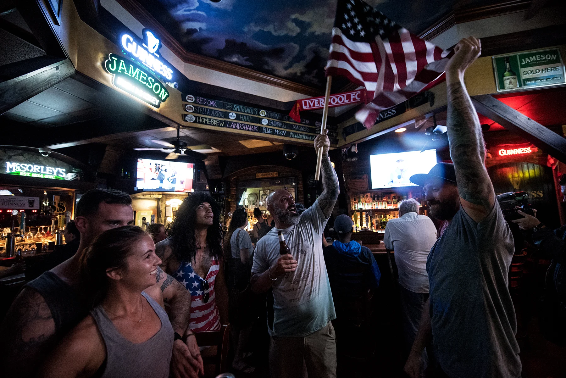Kristin Henry (front/left), Paddy McGrave (back/left), and Jeff Egyp, react to George (center) and Andy Guiles flying the American Flag inside Slainte Irish Pub. is one of two bars open for business despite the expected landfall of Hurricane Florence in Wilmington, NC, USA, September 13, 2018.