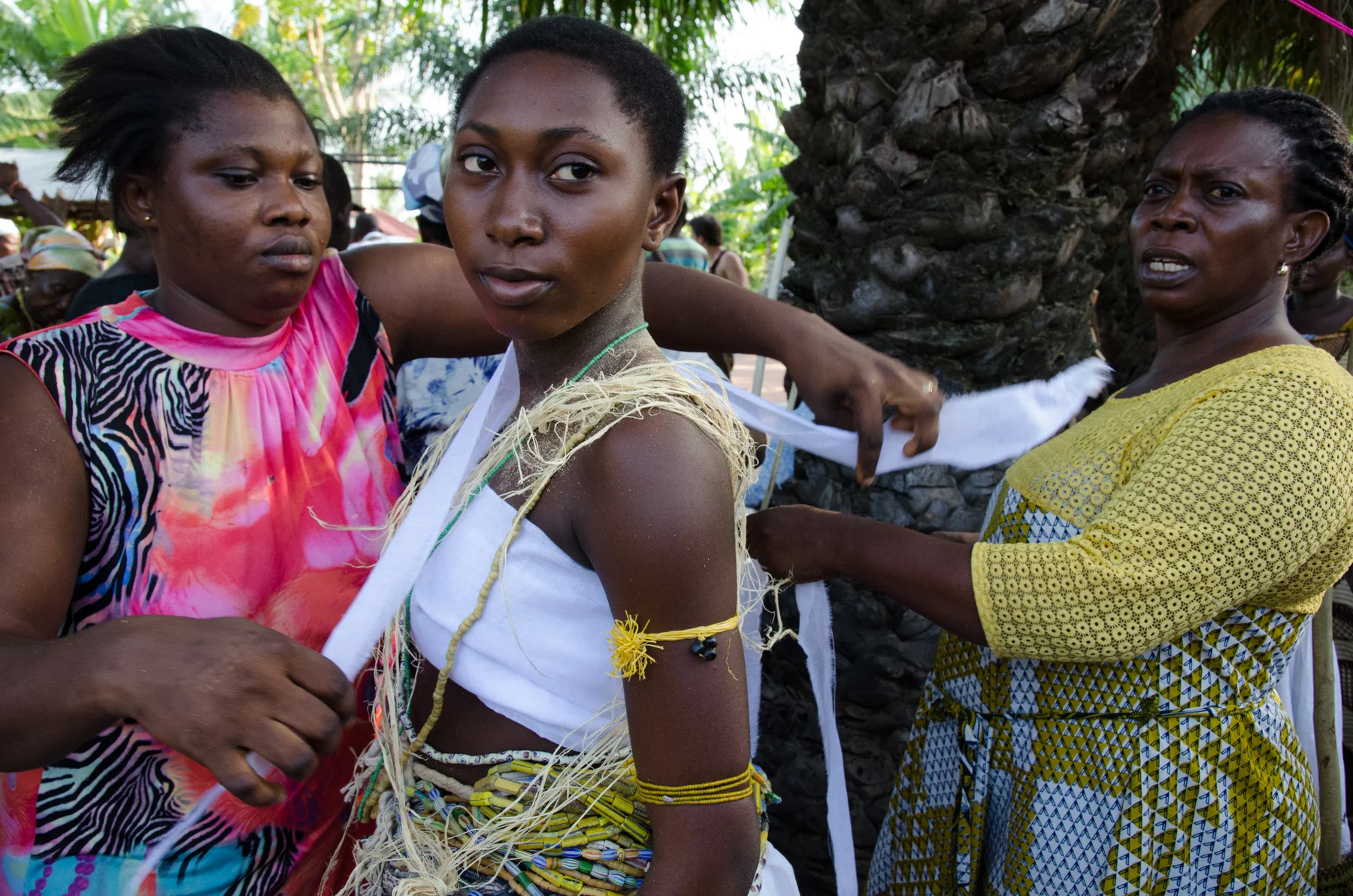 Young woman is prepared for the Dipo Ceremony by women in her community. 