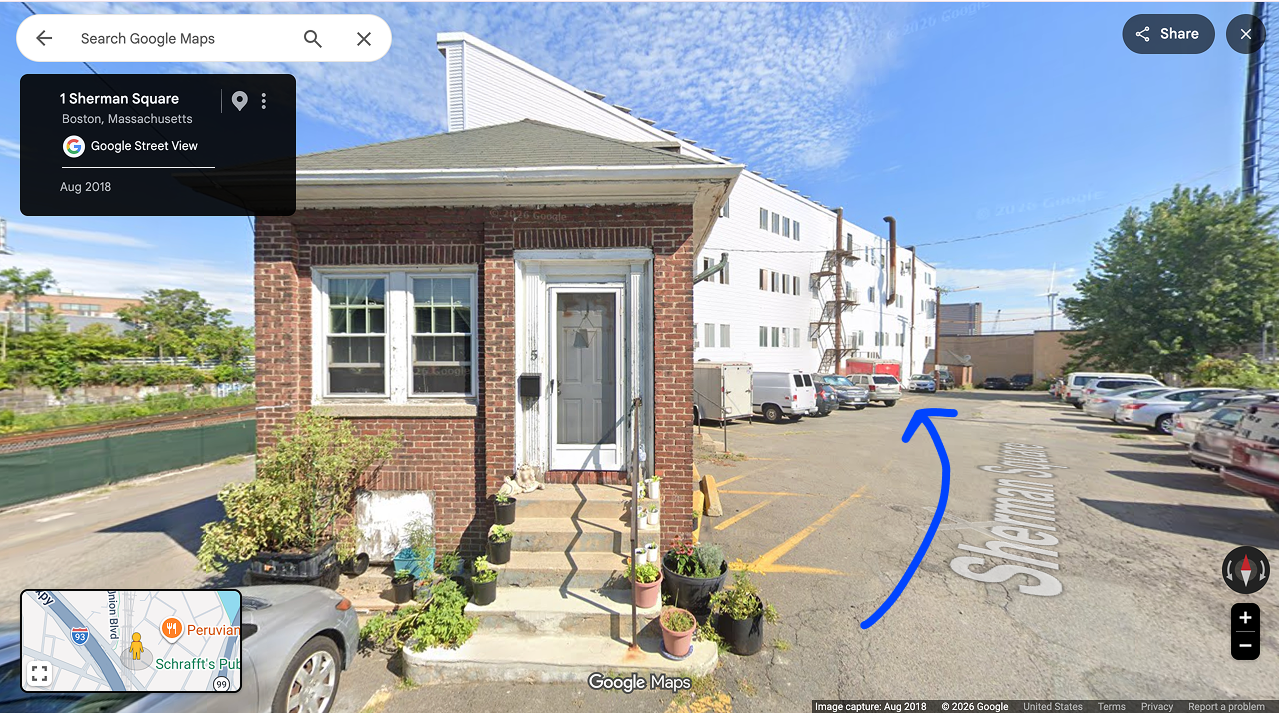 Behind the tiny brick house is a large white building, this is where you're going!