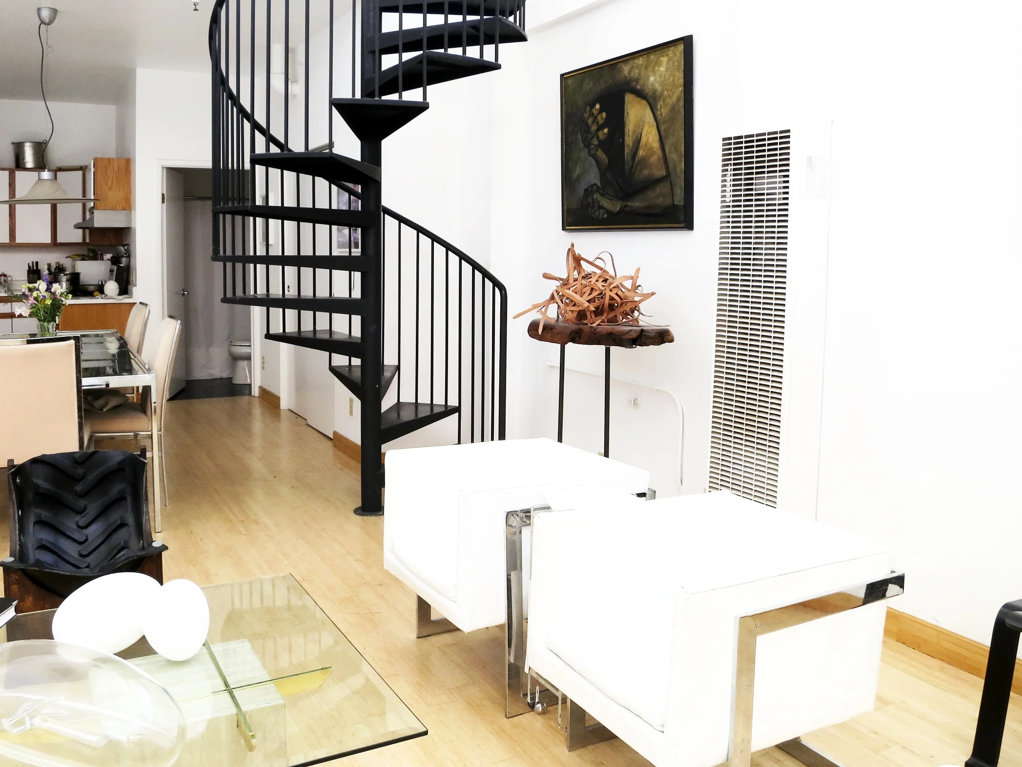 Basil Racuk, a handbag designer and leather artisan, lives in a two-story house that’s home to his collection of iconic furniture, artwork and objects. “The living space on the upper level is filled with light and the lower level, where I have my atelier, is completely cave-like. I love having the two different worlds” he muses. A dramatic wrought iron spiral staircase anchors the living room and connects the two floors