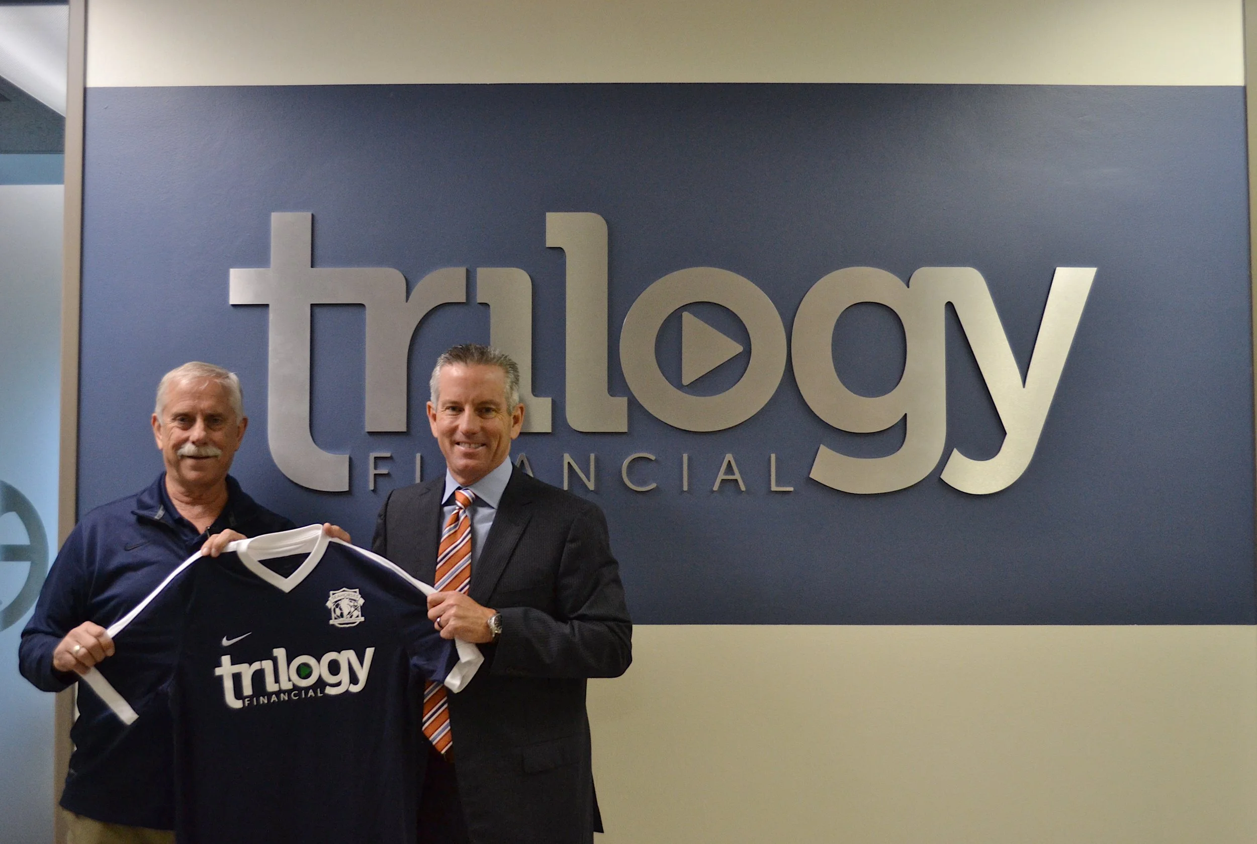 PDL GM, Mark Schrock, stands with President of Trilogy Financial, Jeff Motske, while holding the new away jersey with Trilogy sponsorship. 